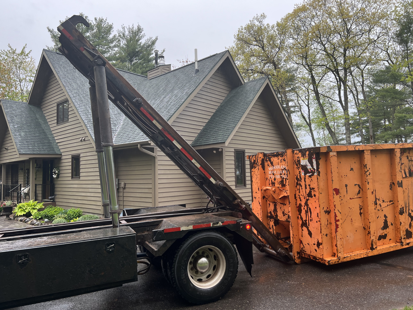 Rolloff truck picking up dumpster at home