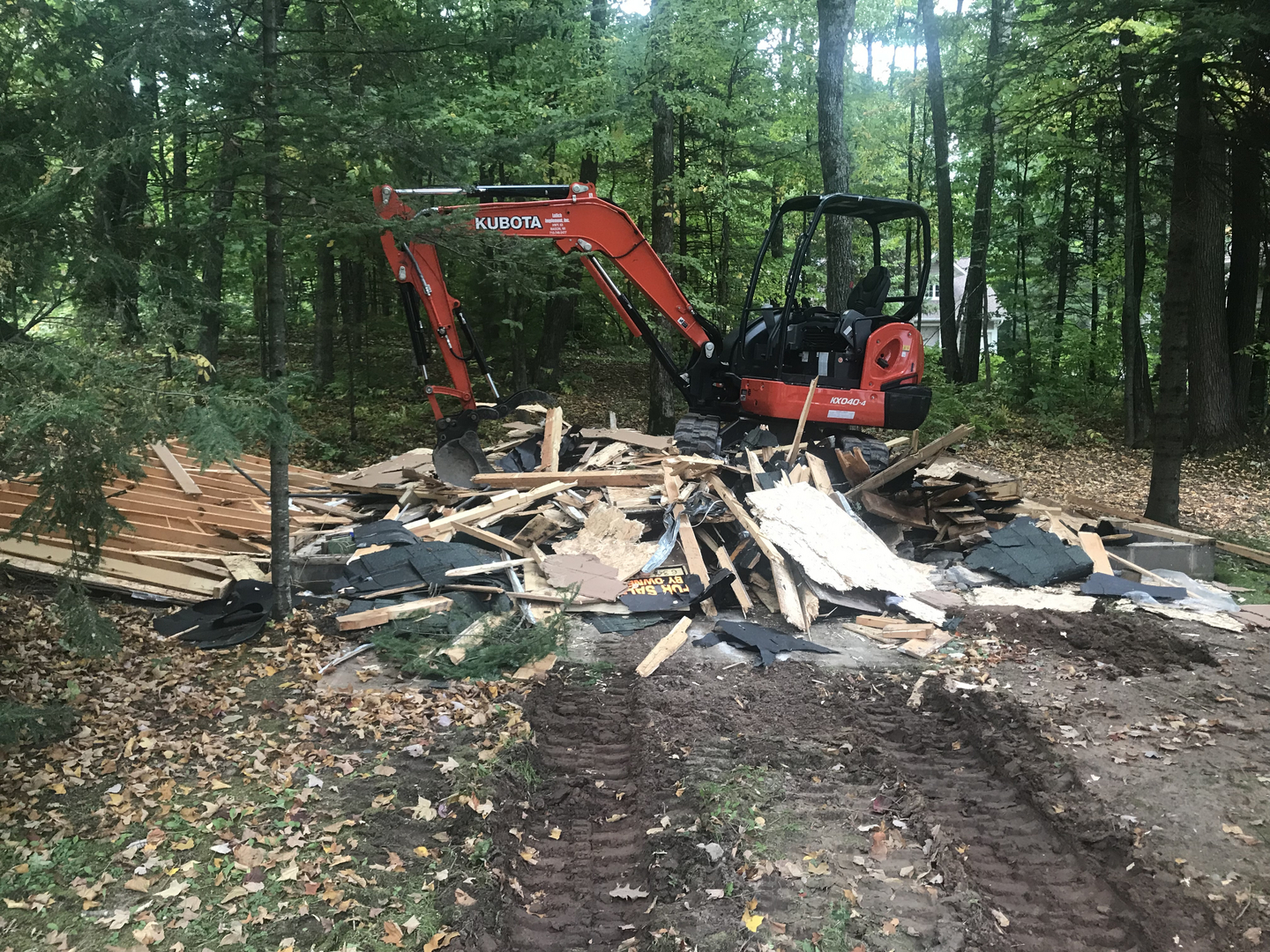 Kubota excavator demolishing garage with pile of debris on Round Lake