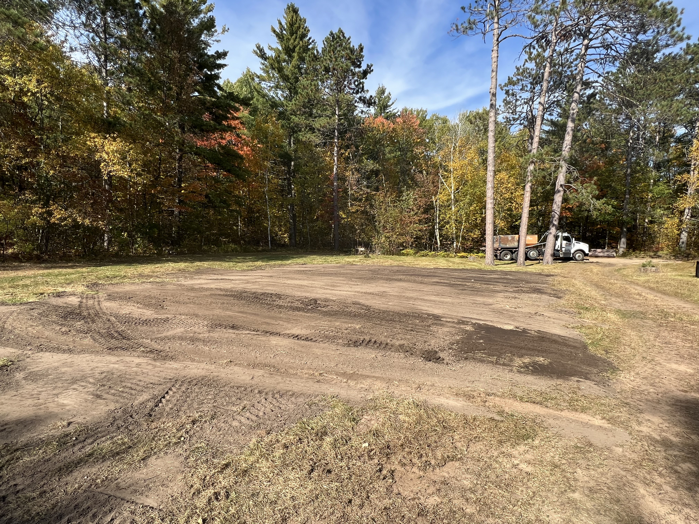 Graded dirt lot with dump truck in background