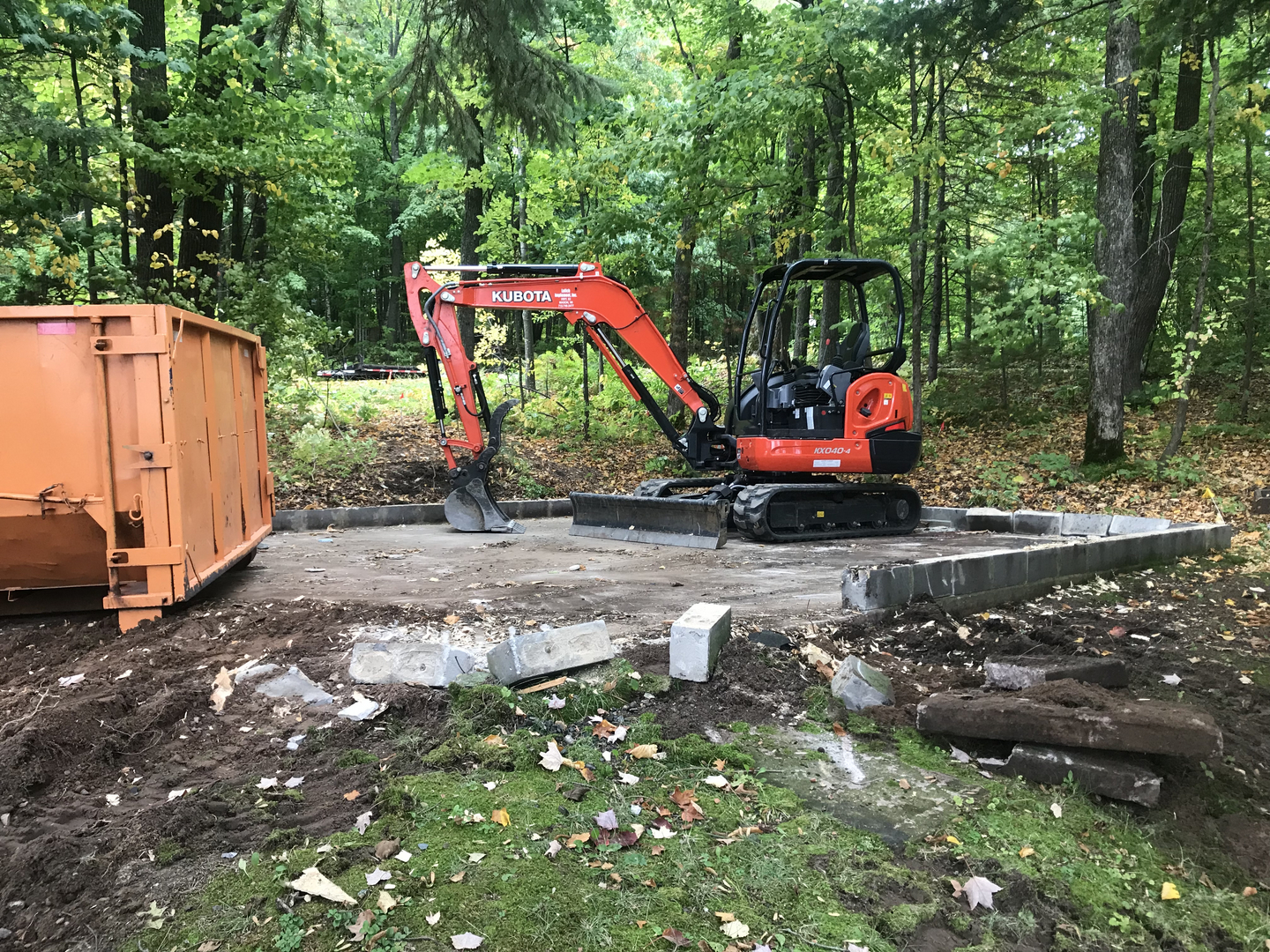 Kubota excavator removing foundation blocks after garage demolition