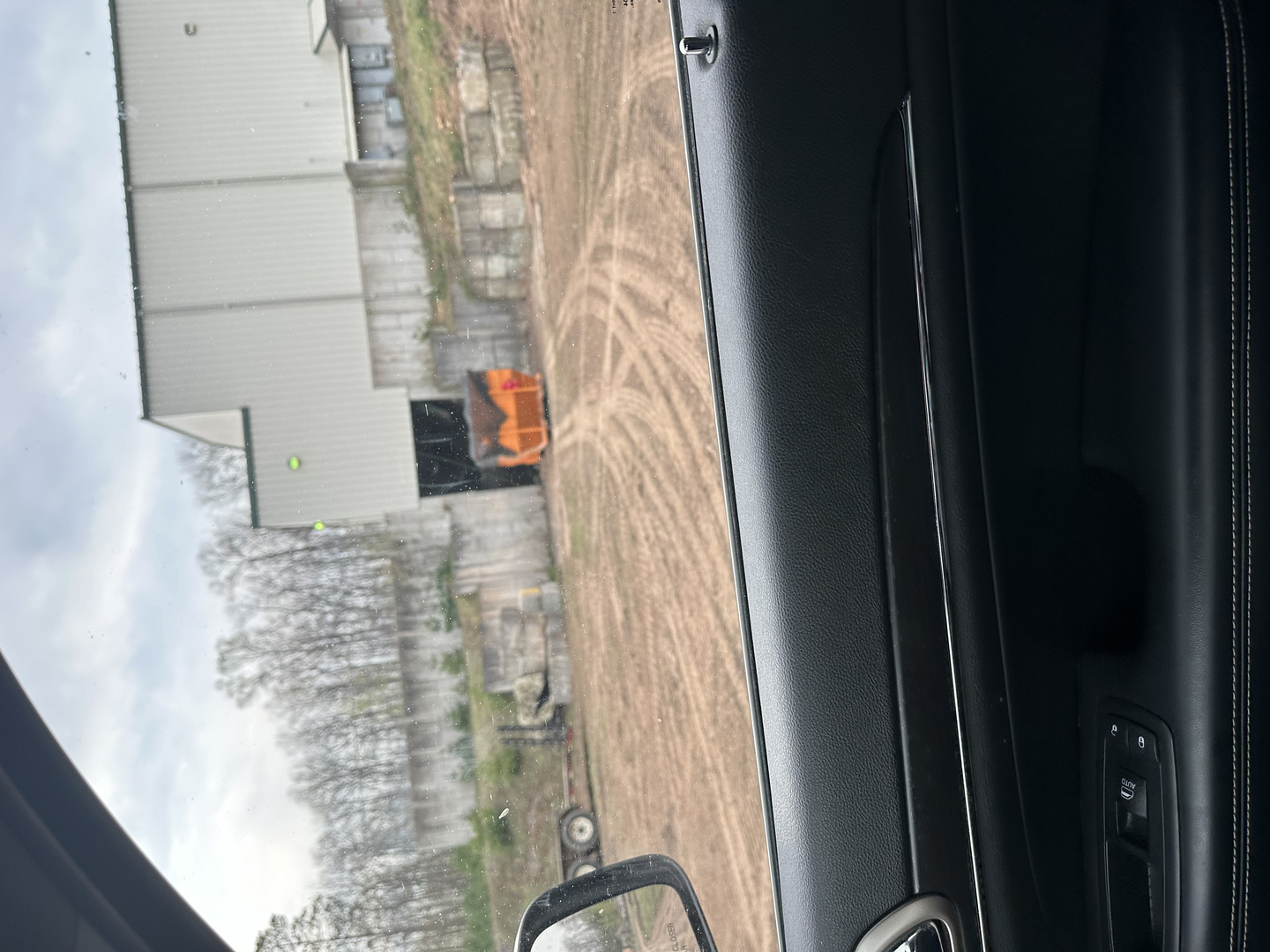 Transfer station building with orange rolloff dumpster viewed from vehicle window