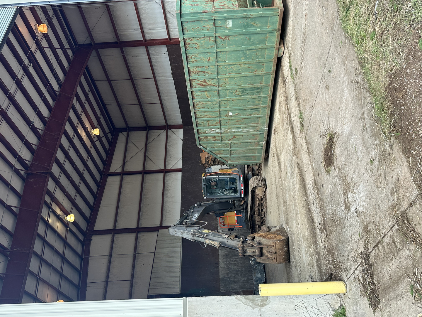 Volvo excavator and rolloff dumpster inside transfer station building